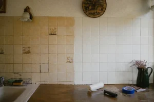 Carrelage mural ancien à moitié repeint montrant l'avant/après d'un camouflage sans dépose